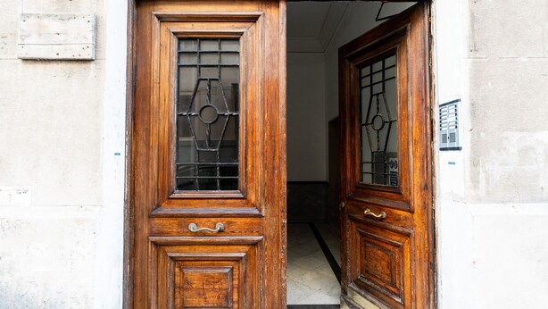 A wooden door with a metal grid window and a small step leading into a hallway. - Umbertina Cozy Apartment by Wonderful Italy (Bari)