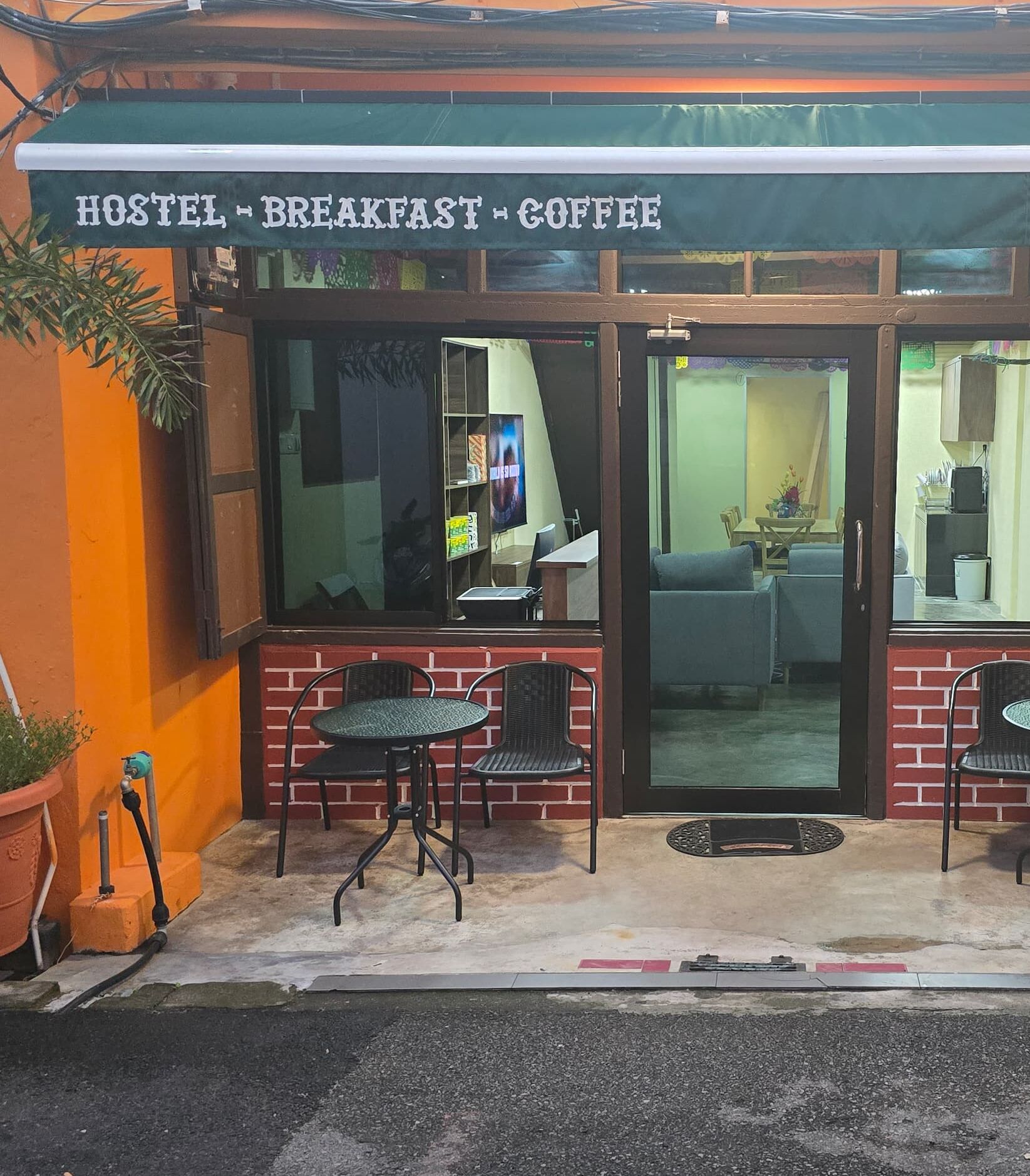 A hostel with a sign reading "HOSTEL - BREAKFAST - COFFEE".