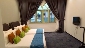 A hotel room with two beds, a TV, and a window with curtains.
