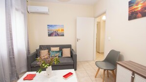 A living room with a grey sofa, a white coffee table, a grey armchair, and a cabinet. - Travelers Nest by Checkin (Heraklion)