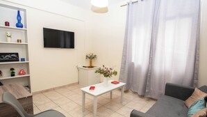 A modern living room with a grey sofa, a white coffee table, and a TV mounted on the wall. - Travelers Nest by Checkin (Heraklion)