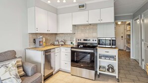 A compact kitchen with white cabinets, a built-in oven, a microwave, and a coffee maker. - Beachfront Condo with Communal Pool & Ocean Views! (Hilton Head Island)