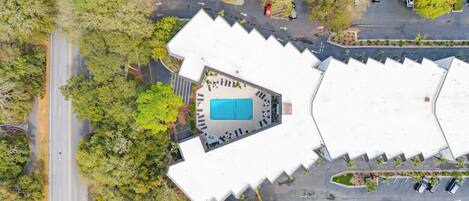 An aerial view of a building with a central courtyard, surrounded by trees and parking spaces.