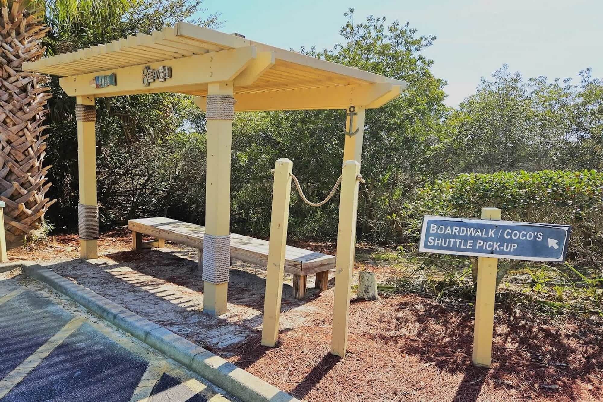 Una estructura de madera con un letrero que indica un paseo marítimo y un punto de recogida de transporte lanzadera.