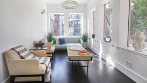 A modern living room with a sofa, armchairs, a coffee table, and a view of the city through large windows.