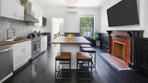 A modern kitchen with a central island, stainless steel appliances, and a black fireplace.