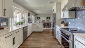 A modern kitchen with white cabinetry, a central island, and a built-in oven. - Lakefront Family Home for 12, w Picturesque Views (Granite Shoals)