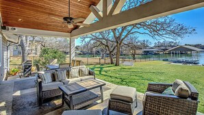An outdoor patio with a ceiling fan, wicker furniture, and a view of a lake and trees. - Lakefront Family Home for 12, w Picturesque Views (Granite Shoals)