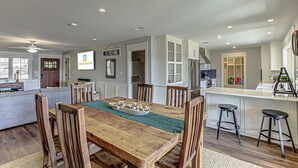 A spacious kitchen with a wooden dining table, bar stools, and a built-in island. - Lakefront Family Home for 12, w Picturesque Views (Granite Shoals)