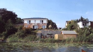 Ein Haus mit einer Steinbrücke, umgeben von Wasser und Vegetation.