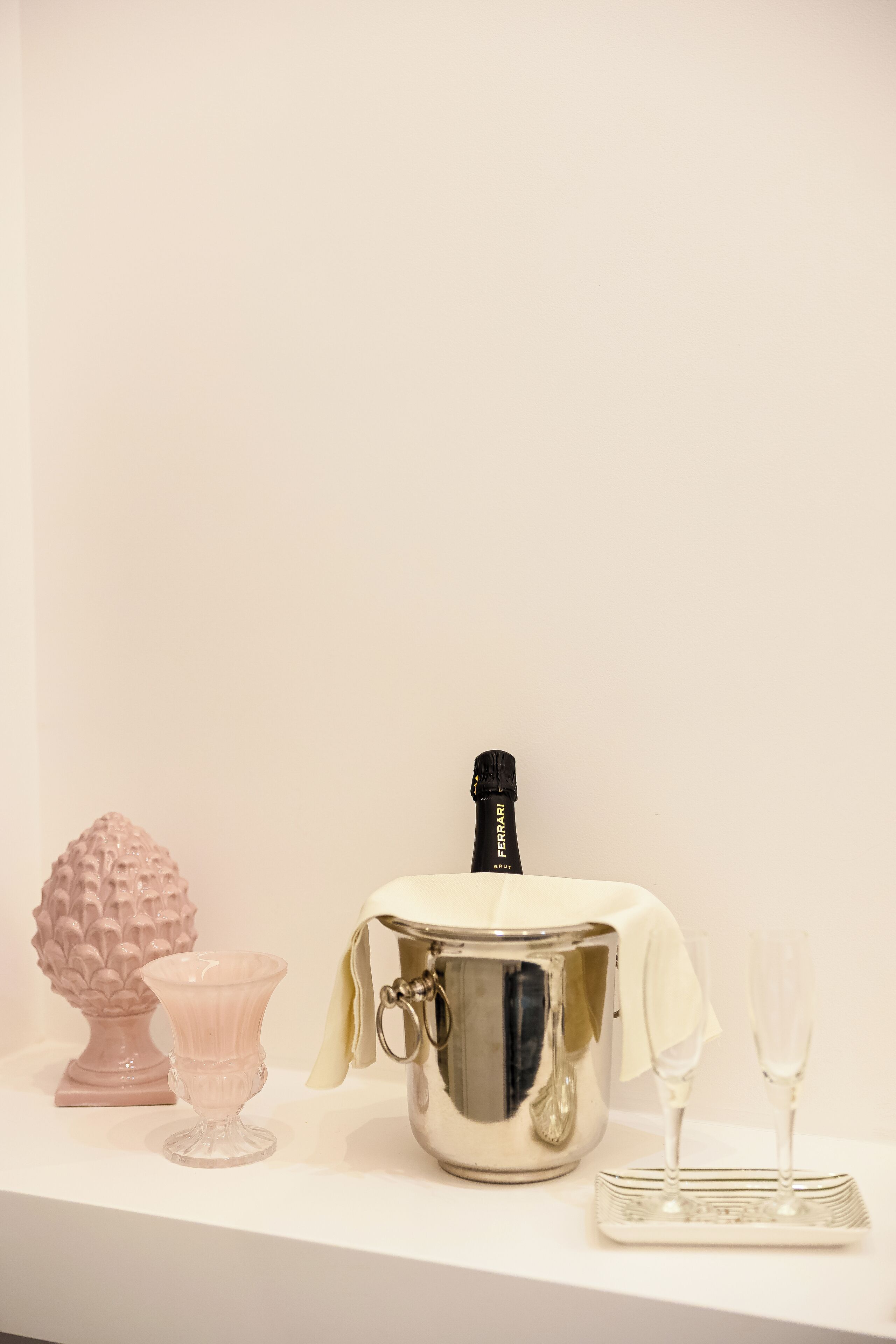 A champagne bucket with a bottle, two glasses, and a decorative item on a white surface.
