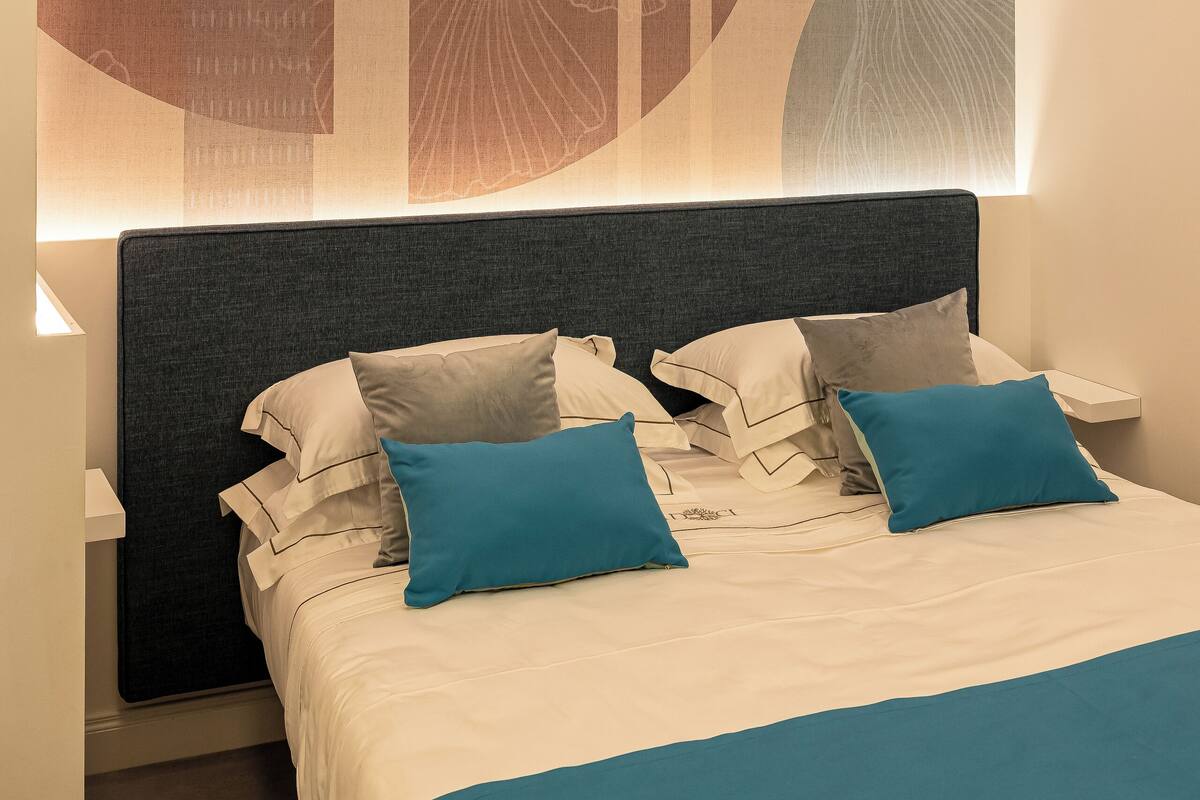 Un dormitorio moderno con una cama grande, cabecera y una obra de arte colgada en la pared.