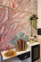 Una habitación con pared texturizada, televisor, una pequeña mesa con un sombrero y un bolso, y una lámpara.