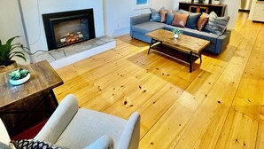 Un salon moderne avec une cheminée, un téléviseur à écran plat fixé au mur, un ensemble de canapés et une table basse en bois.