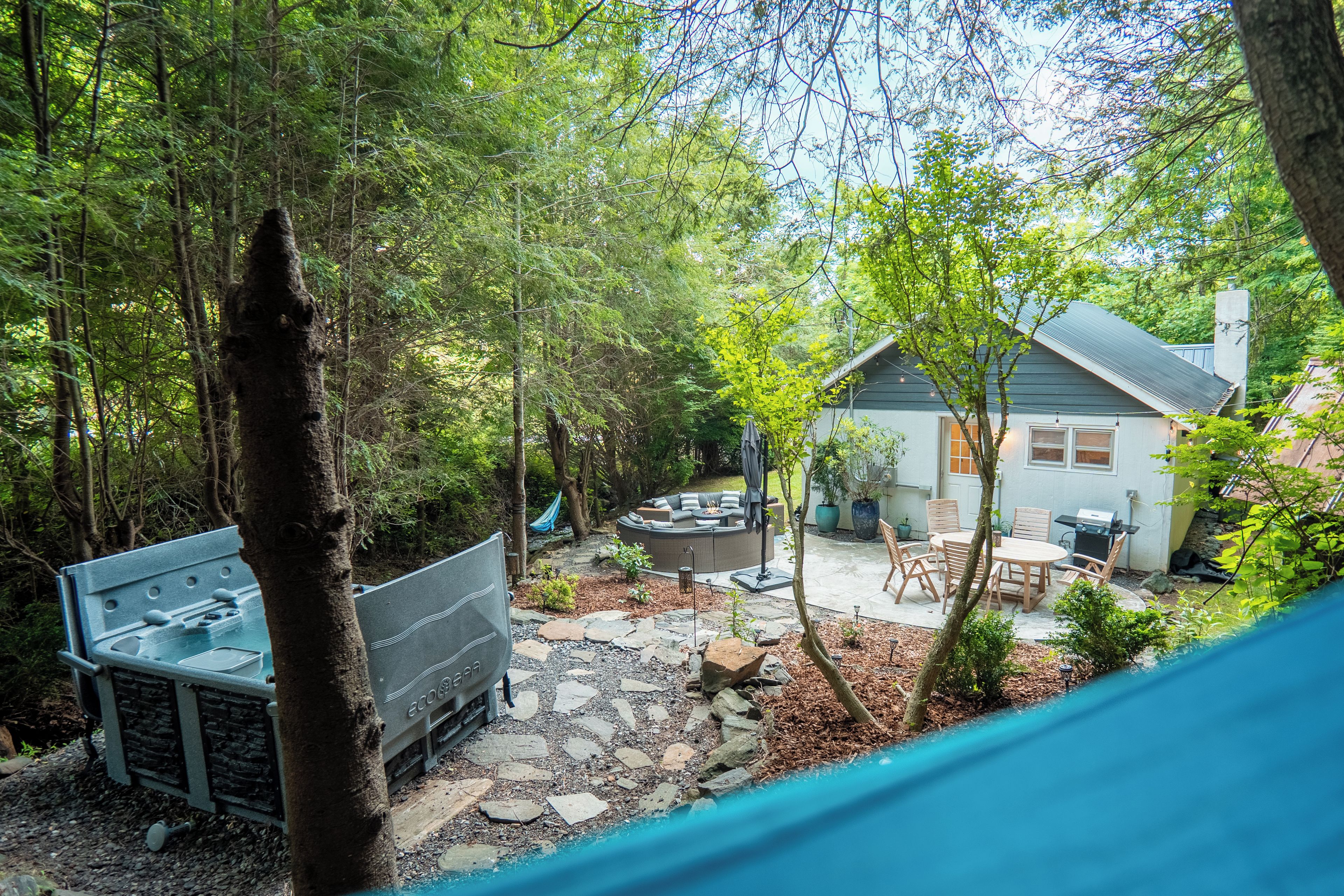 Ein Garten mit einer Steinterrasse, Gartenmöbeln und Grillplatz.