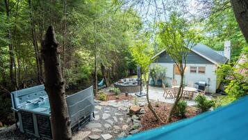 Ein Garten mit einer Steinterrasse, Gartenmöbeln und Grillplatz.