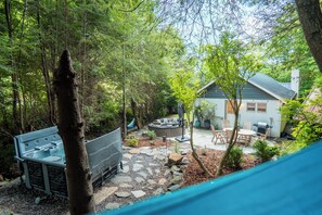 A backyard with a stone patio, outdoor furniture, and a grill area. - Cozy Cottage in Todd - Hot Tub, Outdoor Oasis (Todd)