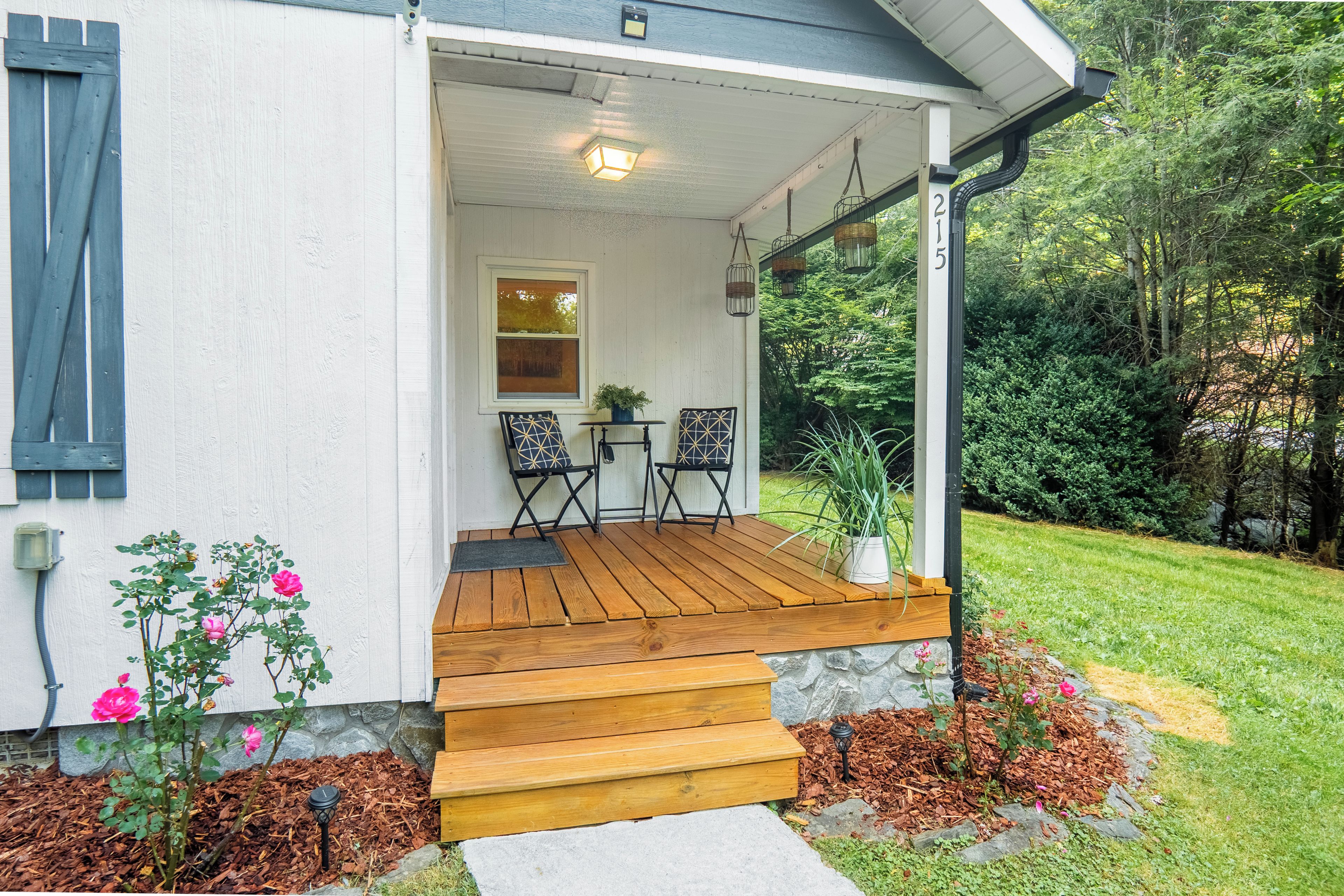 A house with a wooden porch, a small table with chairs, and a potted plant.