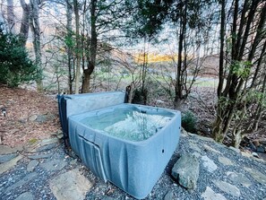 Un jacuzzi en zona boscosa sobre suelo rocoso.