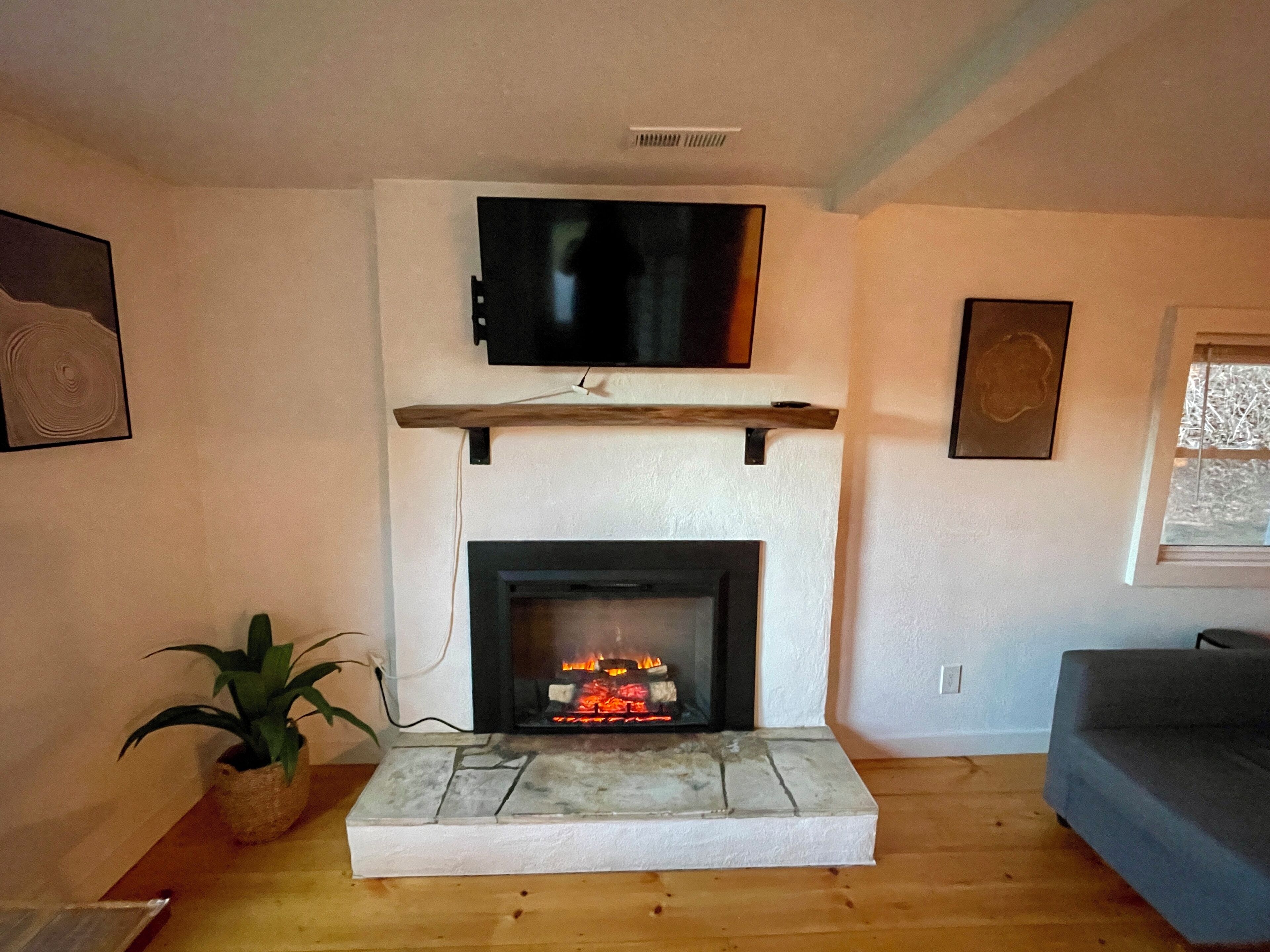 A living room with a fireplace, a mounted TV, and a sofa.
