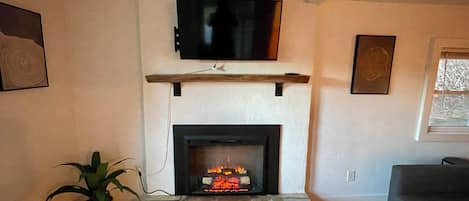 A living room with a fireplace, a mounted TV, and a sofa.