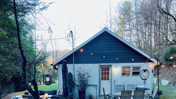 Une maison avec une piscine, un espace extérieur aménagé pour s’asseoir et une véranda bien éclairée.