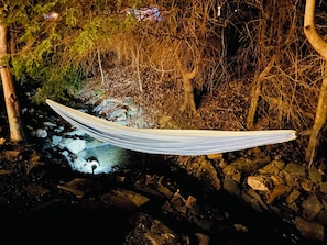 A hammock strung between trees over a rocky stream. - Cozy Cottage in Todd - Hot Tub, Outdoor Oasis (Todd)