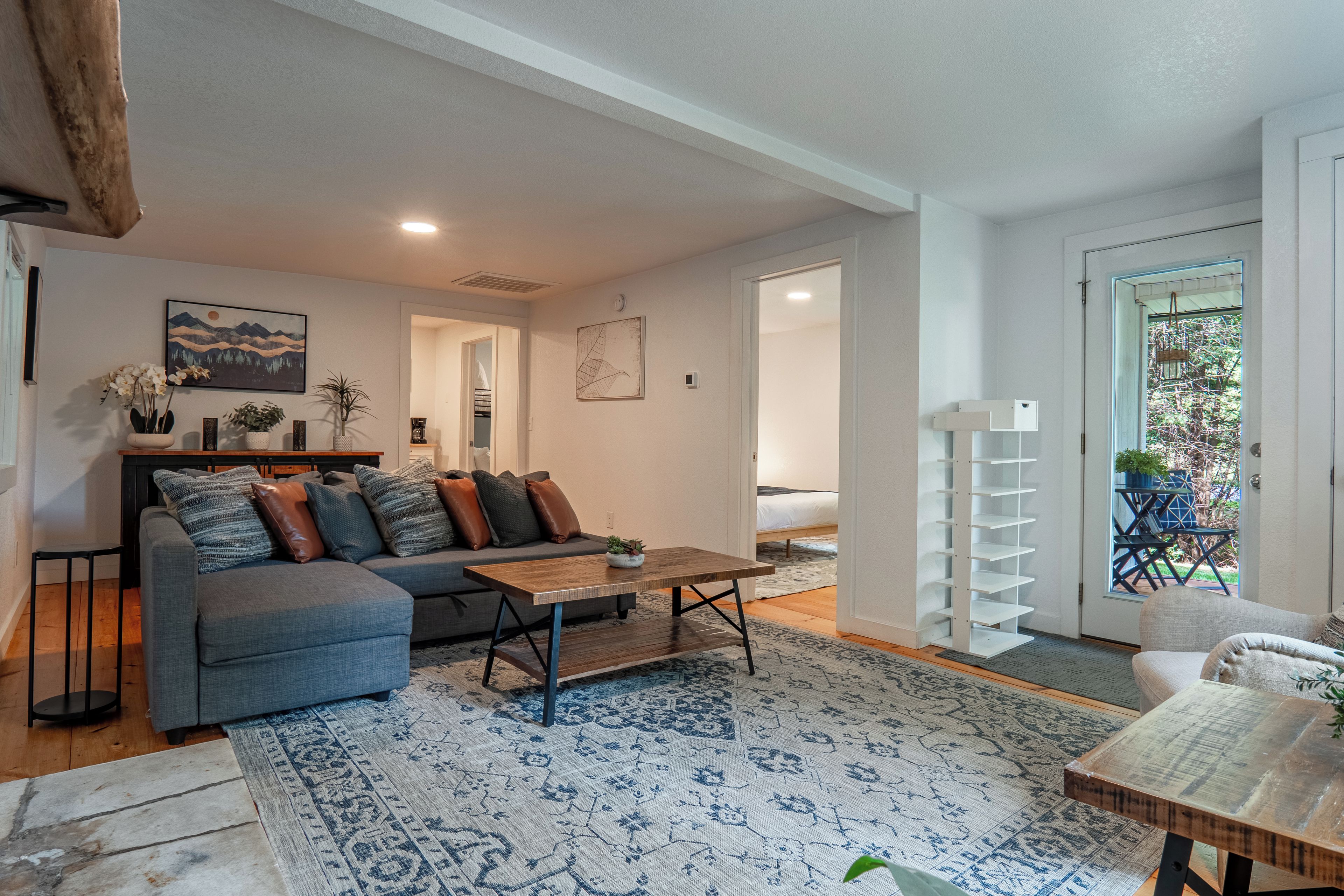 A modern living room with a grey sofa, a wooden coffee table, and a patterned rug.