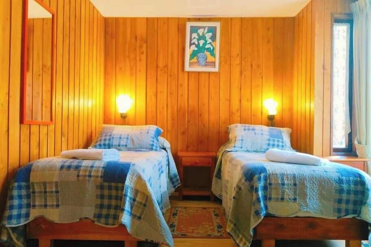 Een kamer met twee bedden, houten wanden en een lijst met een afbeelding aan de muur.