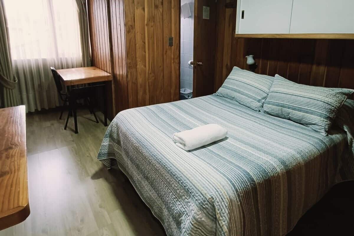 Een kamer met een bed, een bureau en een deur.