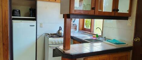 Una cocina compacta con un refrigerador blanco, una estufa y armarios de madera.