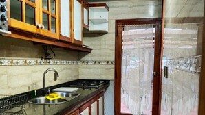 A kitchen with wooden cabinets, a sink, and a stove. - Hostal & Cabañas Don Juan (Villarrica)