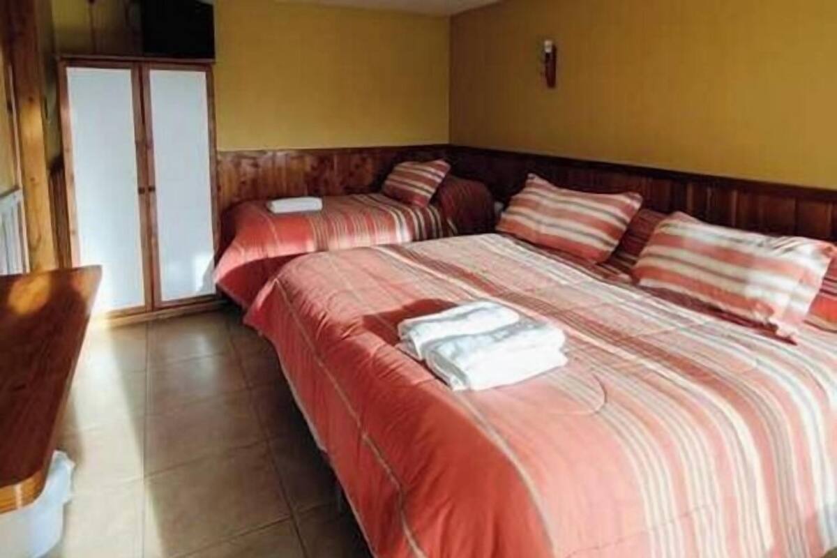 Een hotelkamer met een groot bed, een houten garderobe en een bank.