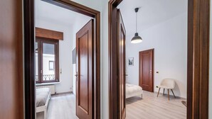 Un apartamento moderno con piso de madera, una cama, una silla y una lámpara colgante.