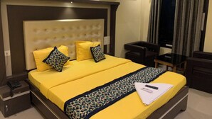 A hotel room with a large bed, a bedside table, a chair, an air conditioning unit, and a window with curtains. - DhamStay Hotel Asish Near Sea Beach Puri (Brahmagiri)