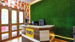 A reception desk with a 'fab hotels' sign, a fire extinguisher, and a green artificial grass wall. - DhamStay Hotel Asish Near Sea Beach Puri (Brahmagiri)