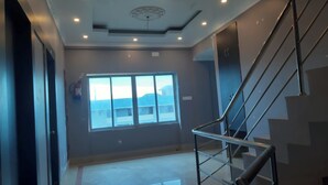 A modern interior with a staircase, a large window with a view, and recessed ceiling lighting. - DhamStay Hotel Asish Near Sea Beach Puri (Brahmagiri)