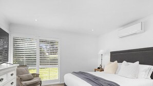 A bedroom with a bed, a nightstand, a lamp, a chair, and a window with blinds.