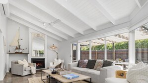 A spacious living room with a fireplace, comfortable seating, and large windows offering a view of the outdoors.