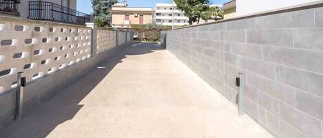 Un camí pavimentat estret, delimitat per murs alts amb una sèrie d'obertures rectangulars.