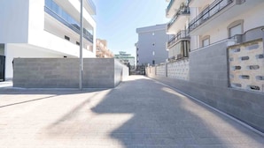 A narrow, paved pathway flanked by modern buildings with balconies and a clear sky. - Perla Nera (Trani)