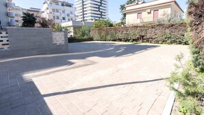 Ein gepflasterter Innenhof mit Backsteinböden, umgeben von Gebäuden mit Balkonen und einem Heckenstreifen.