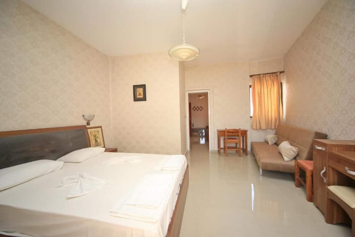 Una habitación de hotel con una cama grande, un sofá, una mesa de madera y una silla.