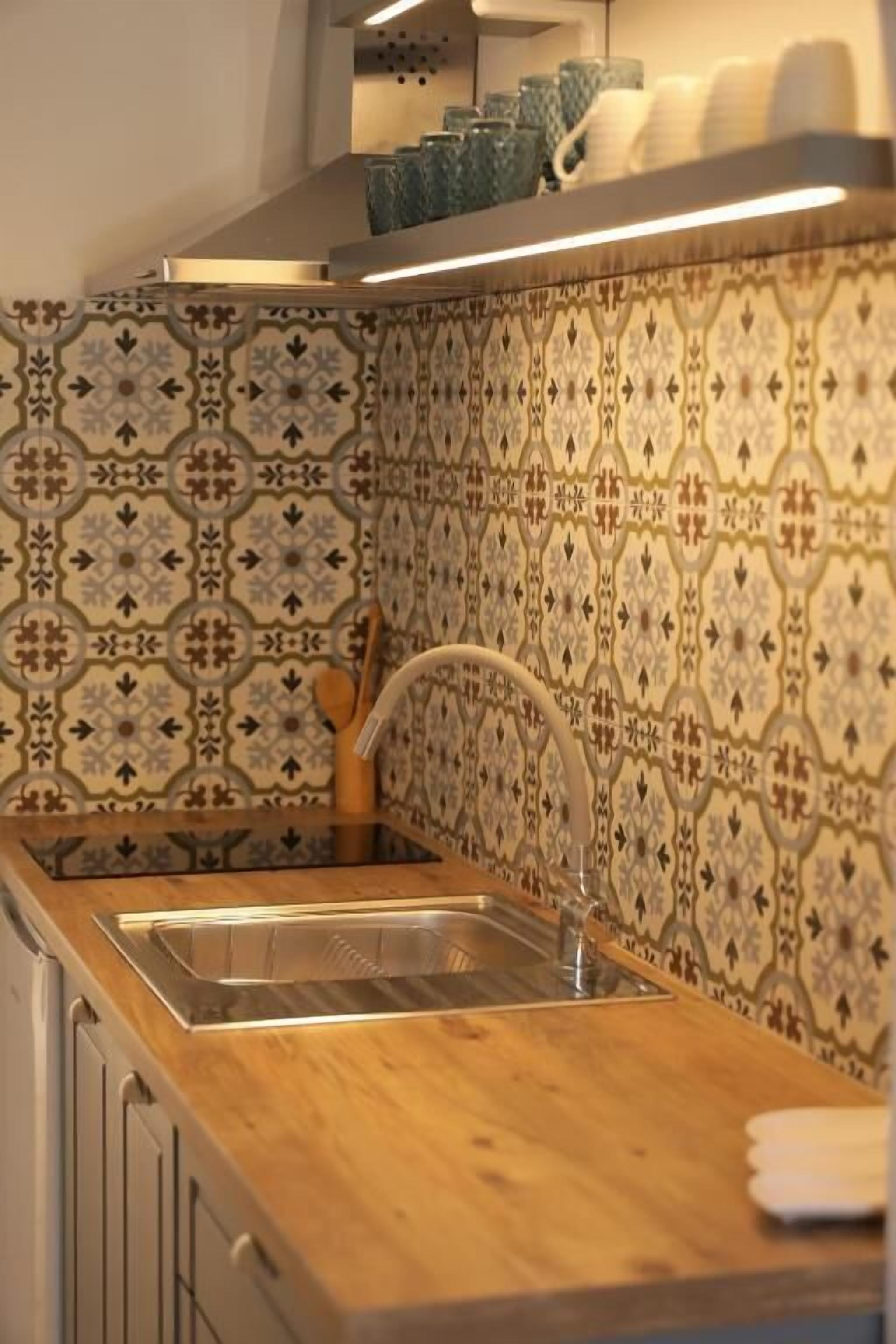 Una cocina con dos fregaderos, encimera de madera y azulejos decorativos en la pared.