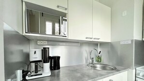 A modern kitchen with white cabinets, a stainless steel sink, a Bosch coffee maker, and a kettle. - City Home Finland (Tampere)