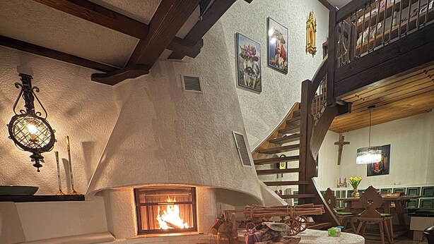 A cozy interior with a fireplace, wooden beams, and a cowhide rug. - Exclusive maisonette apartment with alpine views (Ühlingen-Birkendorf)