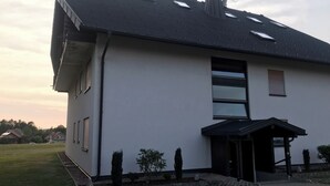 A modern two-story house with a flat roof, multiple skylights, and a small porch. - Exclusive maisonette apartment with alpine views (Ühlingen-Birkendorf)