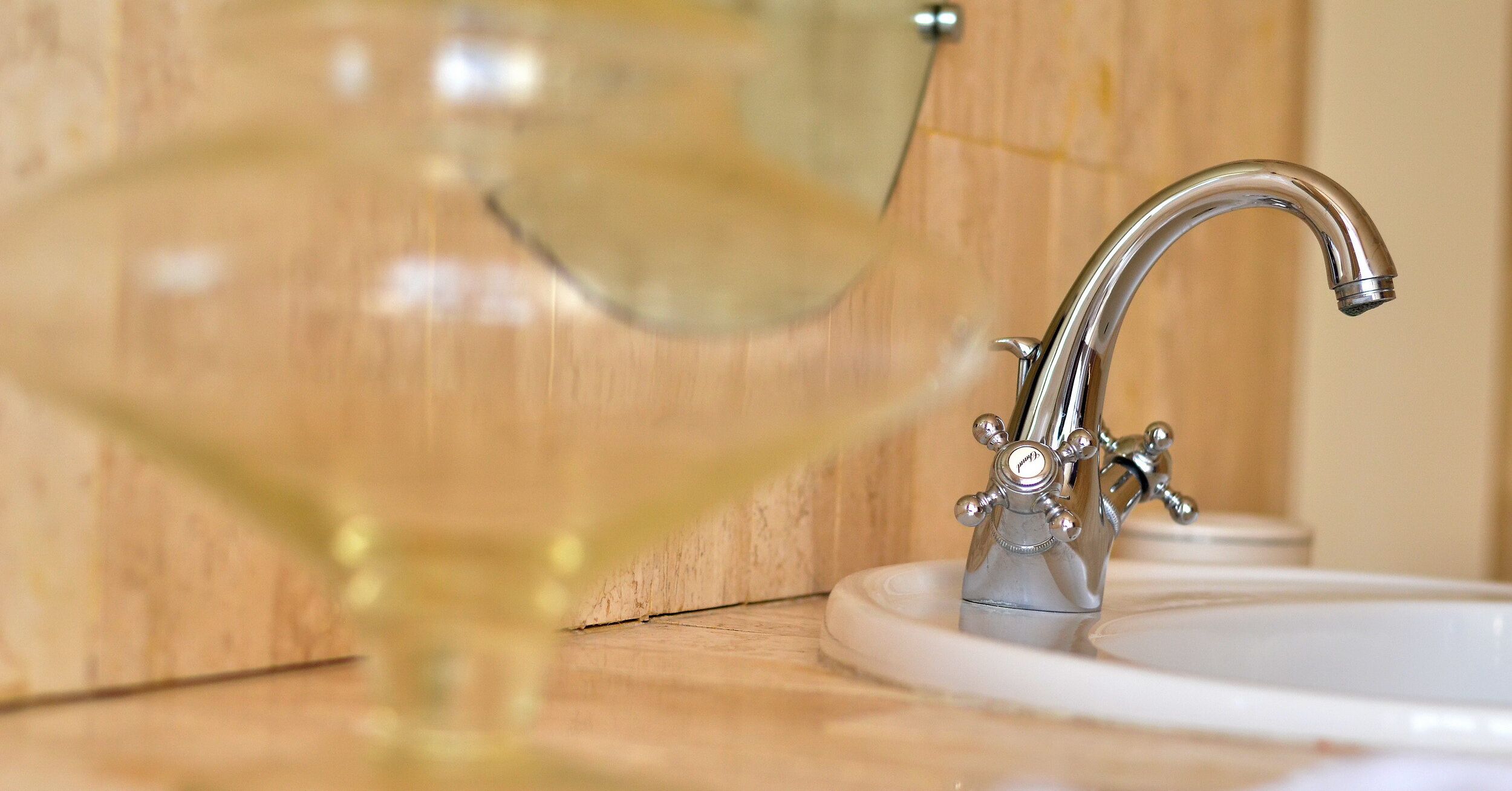 Un lavamanos de baño con un grifo moderno y un vaso de agua.