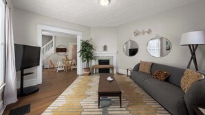 A living room with a TV, sofa, coffee table, and fireplace. - Summit Scholars 1 - For 6 (Columbus)
