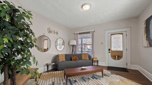 A living room with a sofa, coffee table, and a large plant. - Summit Scholars 1 - For 6 (Columbus)